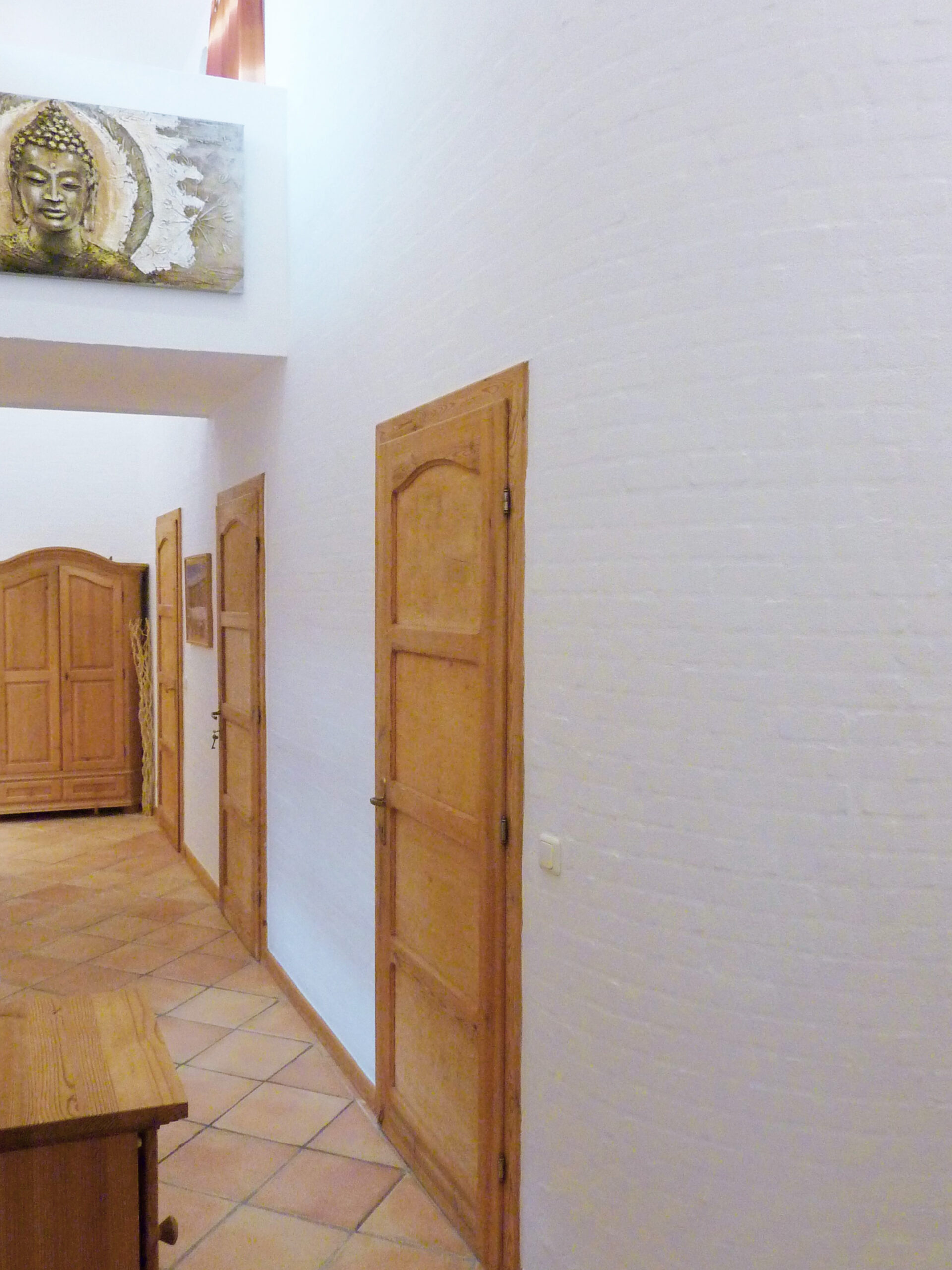 Heller Flur mit Holztüren und Buddha-Gemälde im Mai Thai Siam Massagestudio in Lüchow